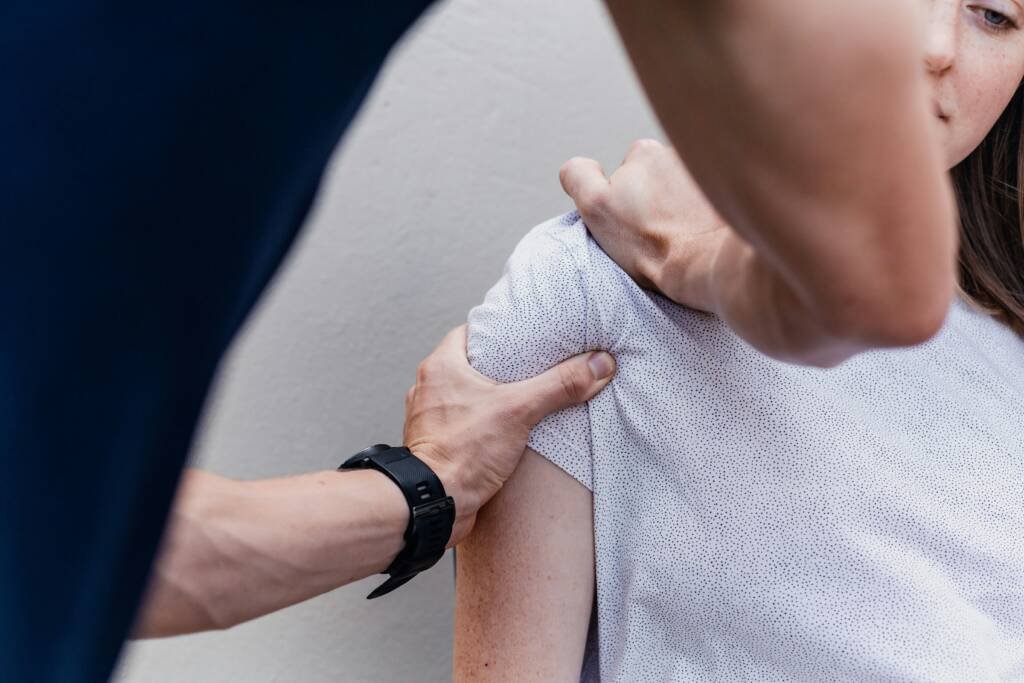 Chiropractor examining a patient's shoulder during a sports injury evaluation in Steele Creek, Charlotte, NC