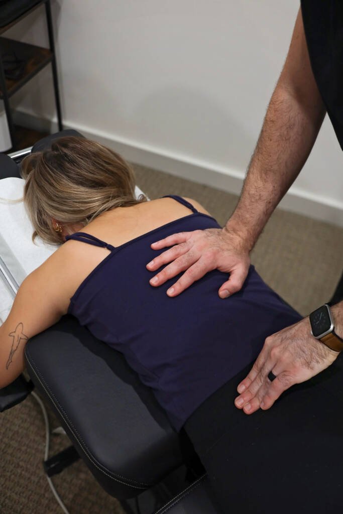 Chiropractor assessing a patient’s lower back during an evaluation for a herniated disc in Steele Creek, Charlotte, NC