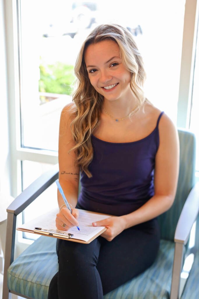 New patient smiling while filling out intake forms in the waiting room