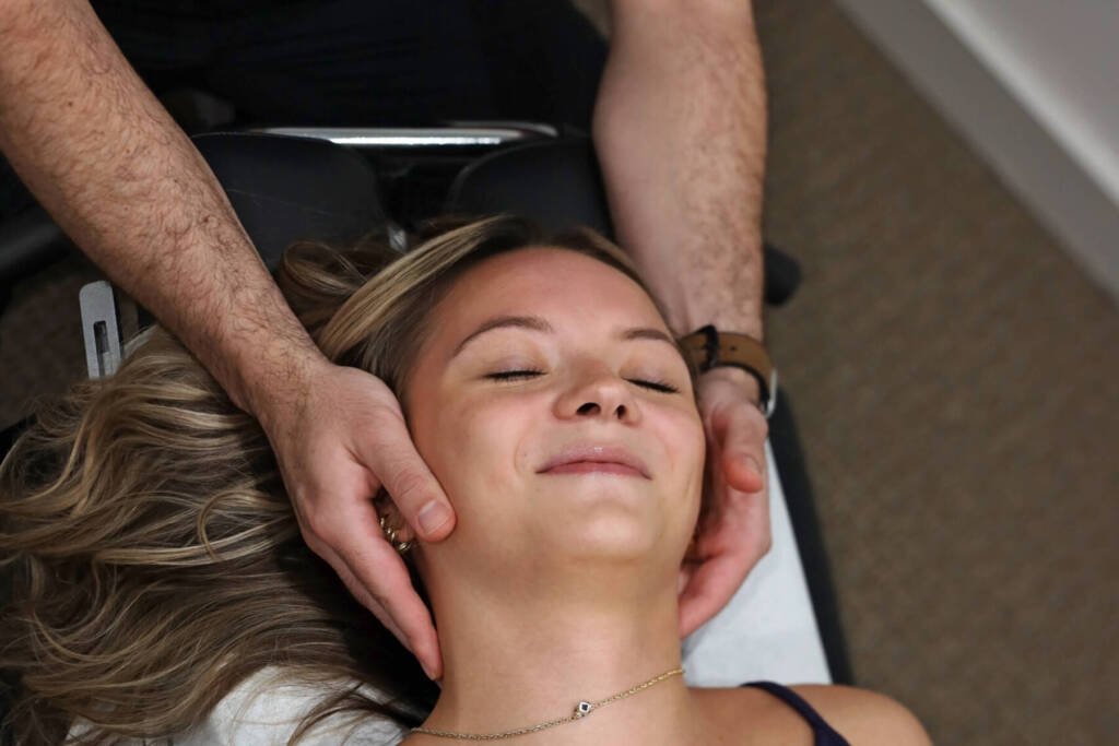Chiropractor cradling a relaxed patient’s head to apply gentle cervical traction at Urgent Chiropractic of Steele Creek