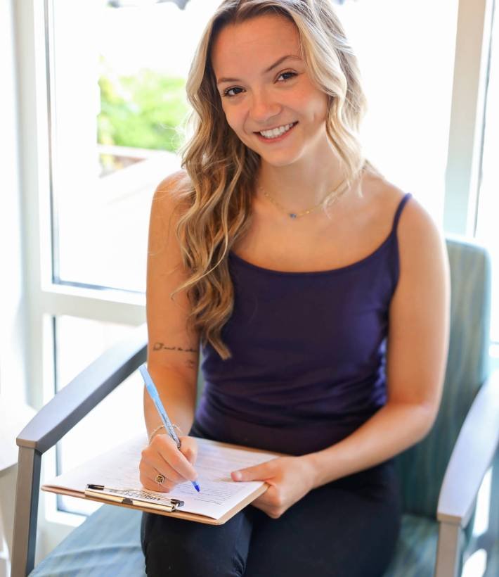 New patient smiling while filling out intake forms in the waiting room